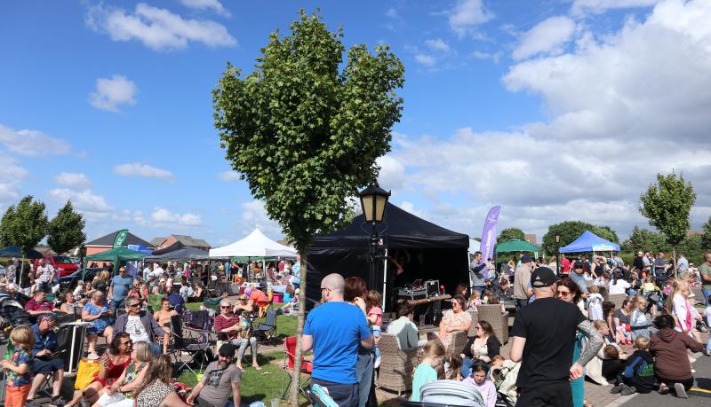 A huge crowed of festival goers sitting in the sunshine.
